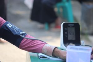person in pink long sleeve shirt checking blood pressure